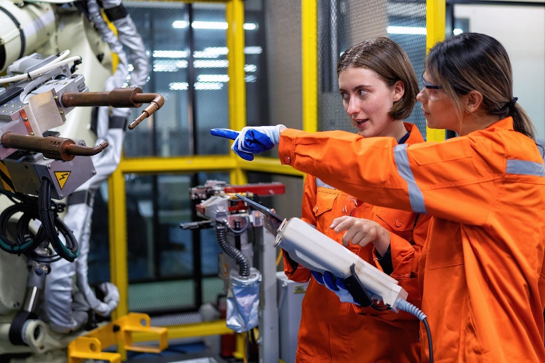 Woman engineer looking at robot machine in the factory